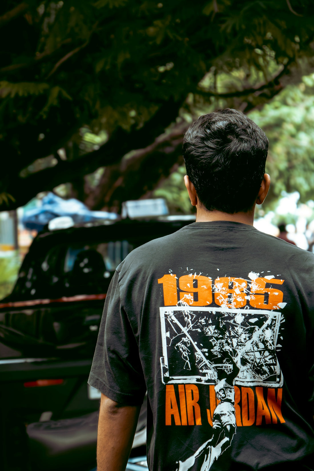 Man wearing a black t-shirt with 1995 air jordan graphic.