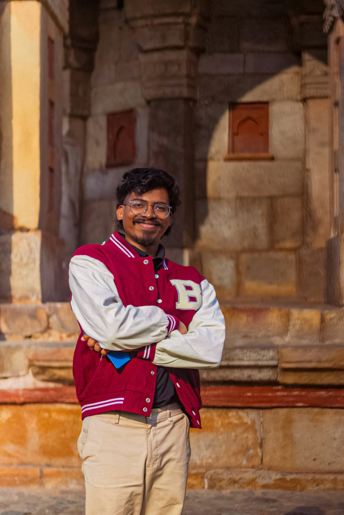 Man in letterman jacket standing in front of stone building