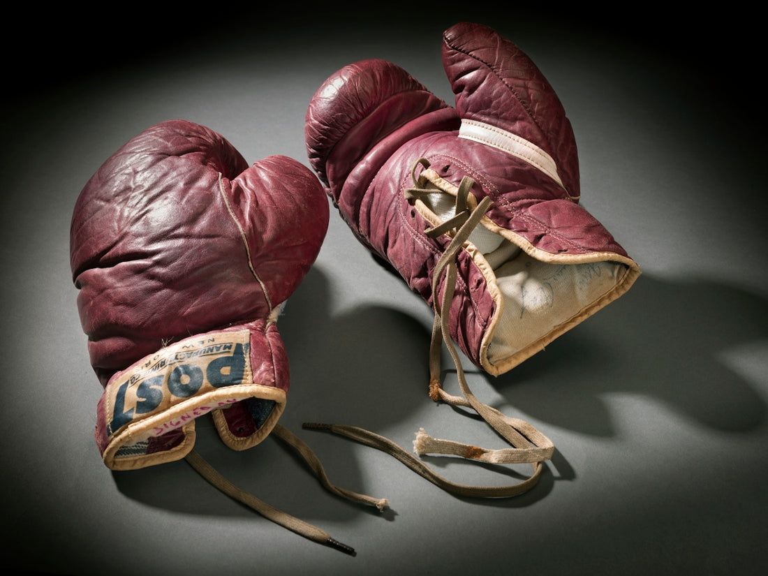 Vintage red boxing gloves with laces on a dark background.