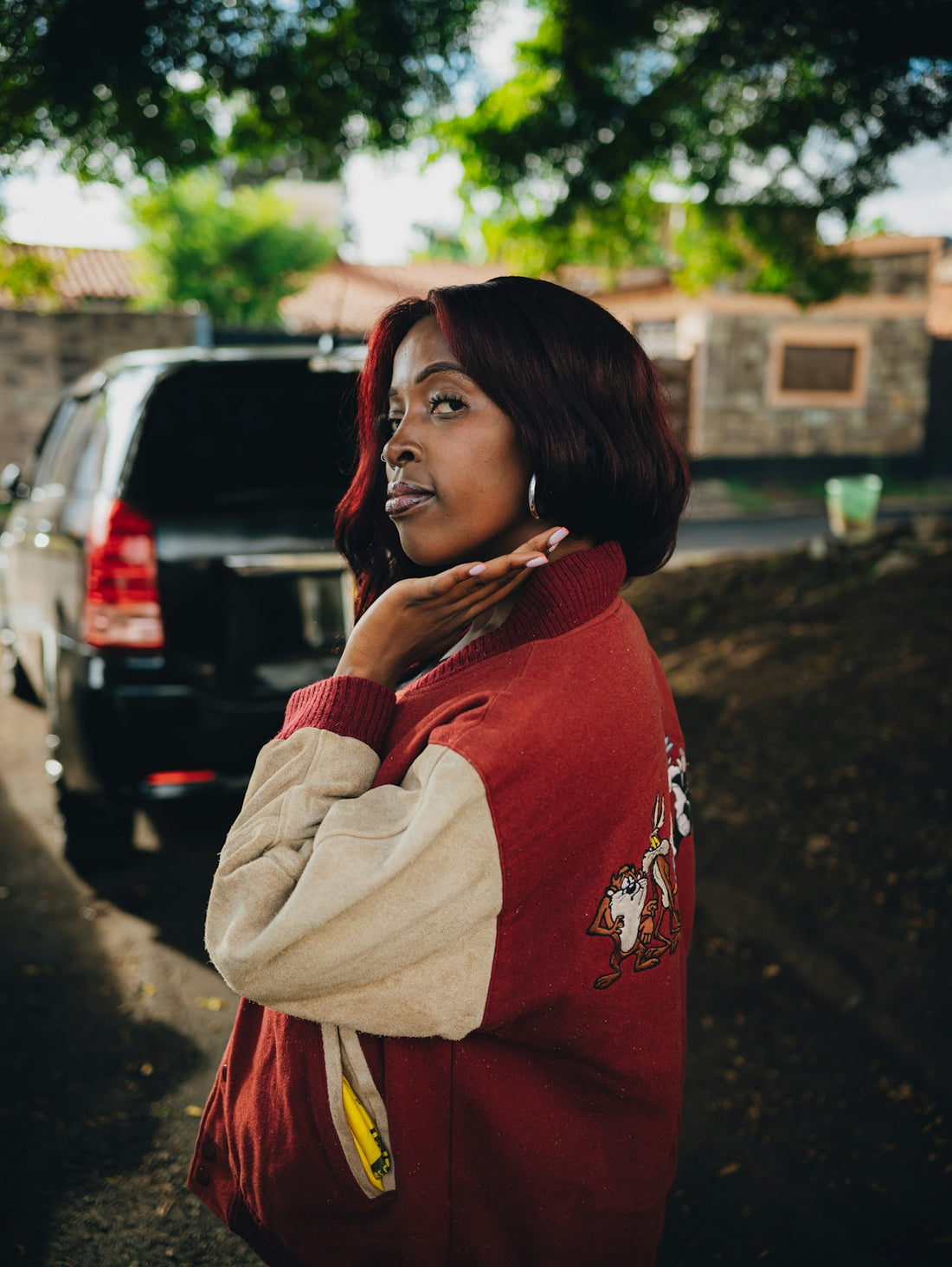 Woman in red jacket poses on a street.